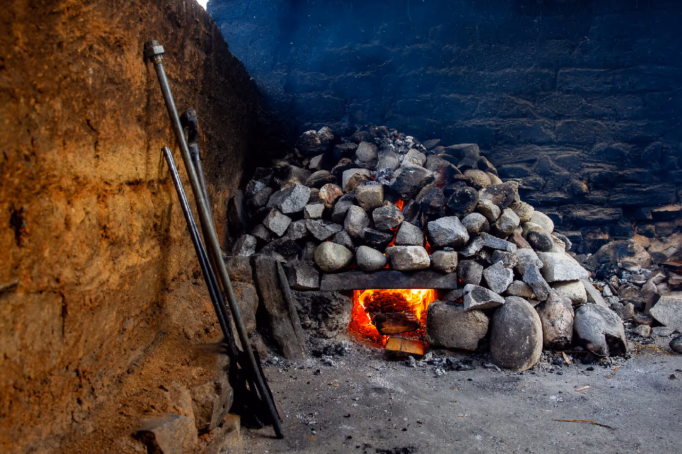 Traditional Bhutanese hot stone bath heating chamber with firewood and river stones stacked above.
