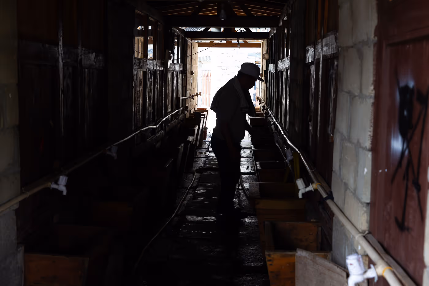 Silhouette of a person walking through a narrow corridor lined with hot stone bath tubs in Bhutan.