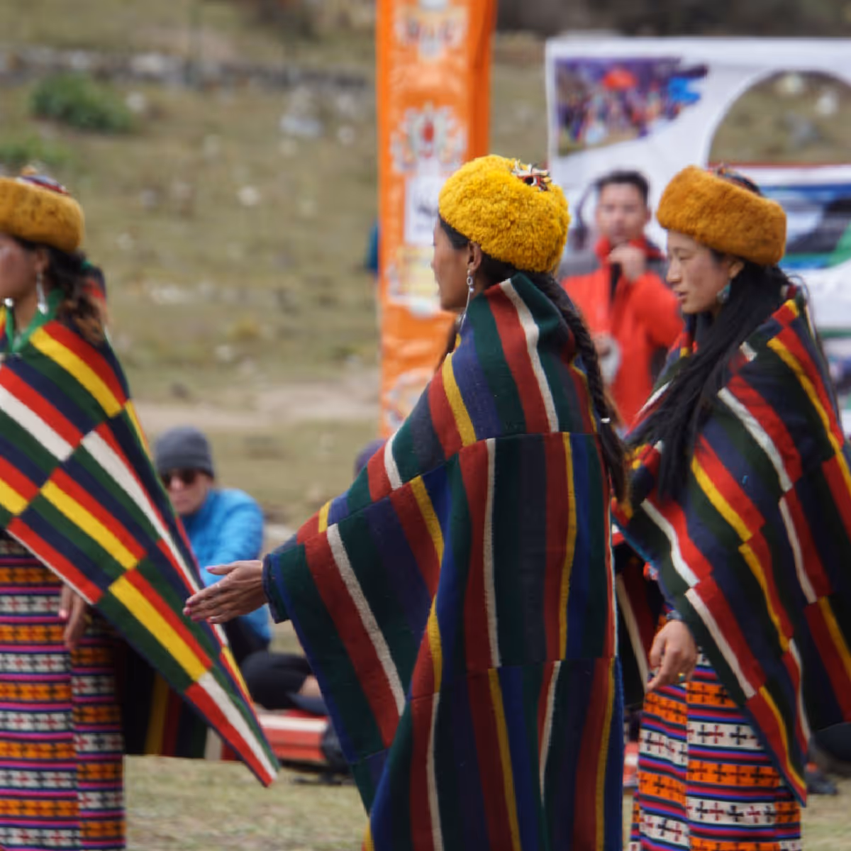 Highland women dressed in bold striped woolen shawls and golden headdresses perform a sacred cultural dance during the Jumolhari Mountain Festival.