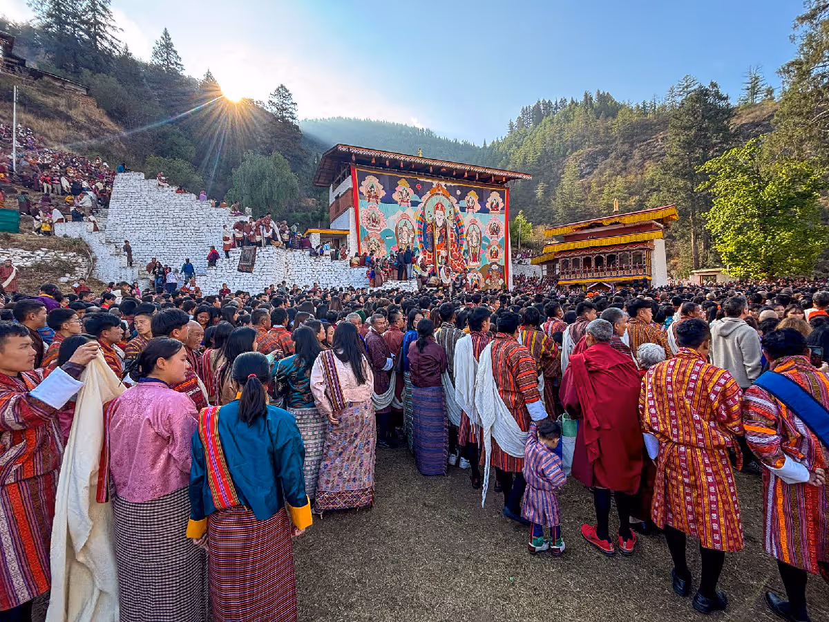 A sea of worshippers in traditional dress gathers at dawn to witness the unfurling of the sacred Thongdrel at Paro Dzong.