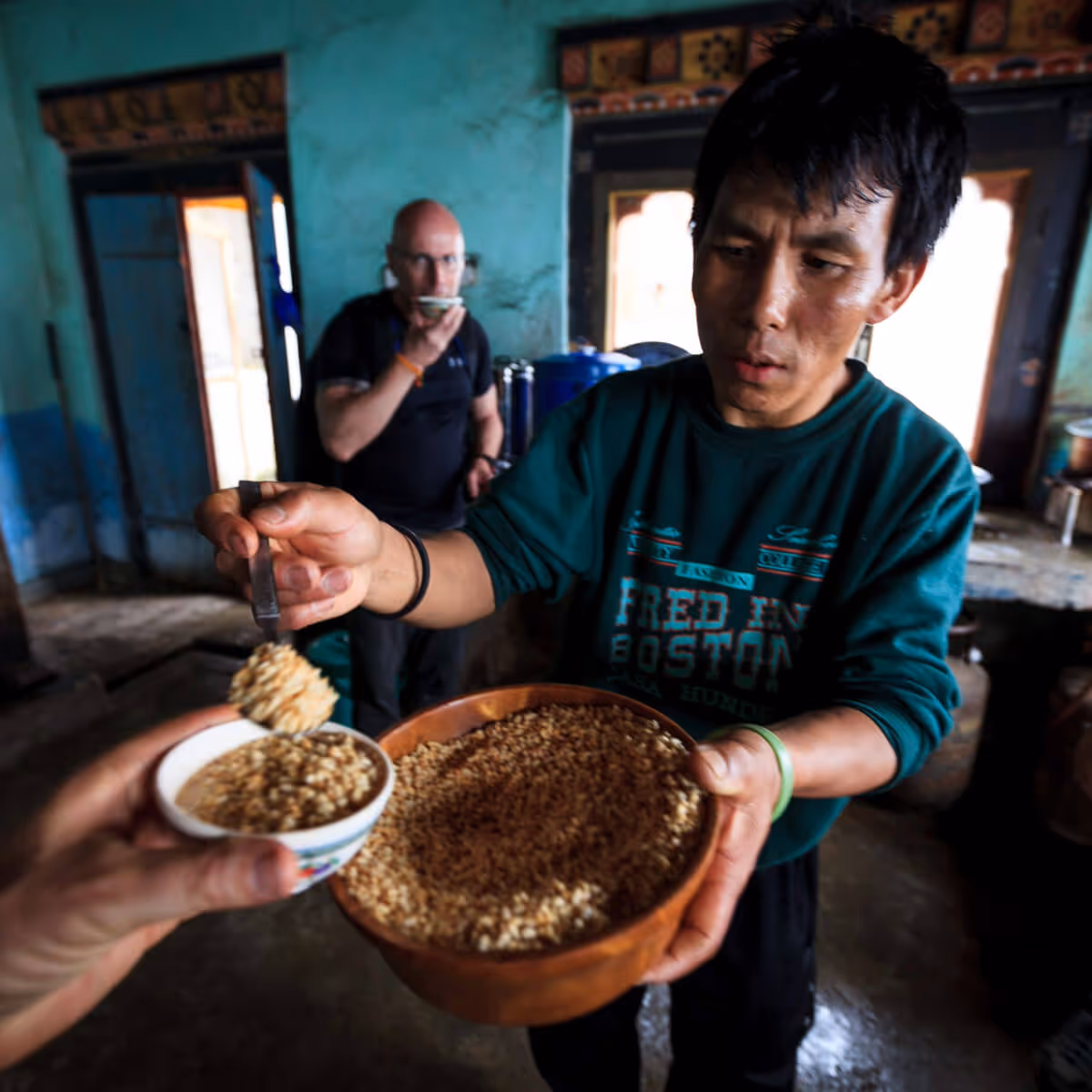 Guest being served tea, roasted rice, and snacks at Talo village