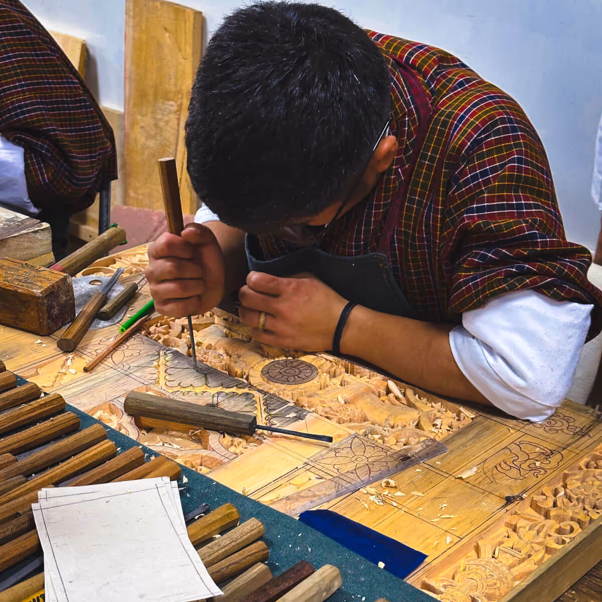 Artisan carving intricate wood designs at Choki Traditional Art School, Thimphu