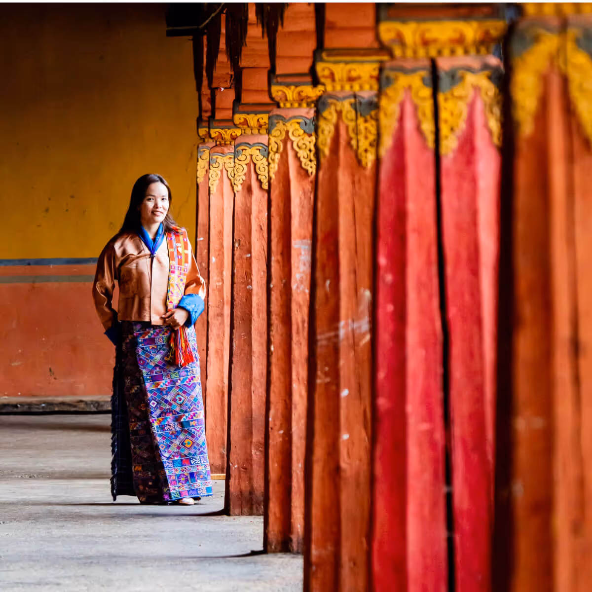 Woman in kira walking along temple corridor, Bhutan.