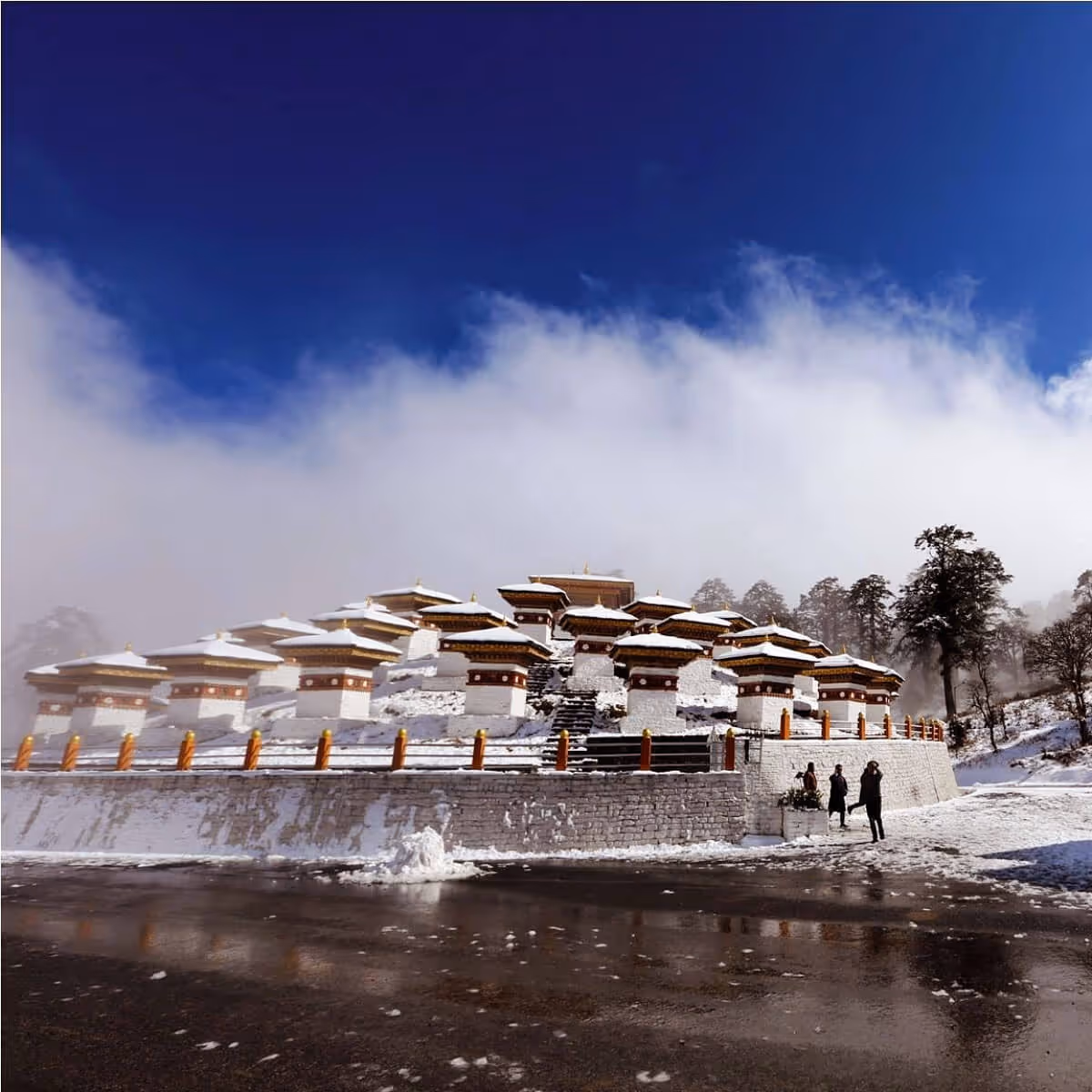 Dochula Pass stupas dusted in fresh snow under a blue sky