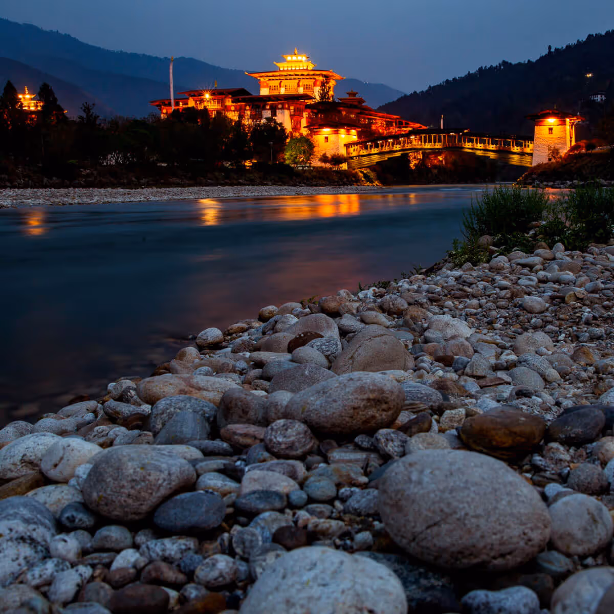 Punakha Dzong illuminated at night beside river in Bhutan.