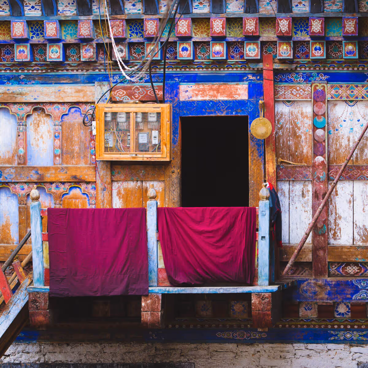 Colorful traditional Bhutanese monastery building with maroon robes hanging.
