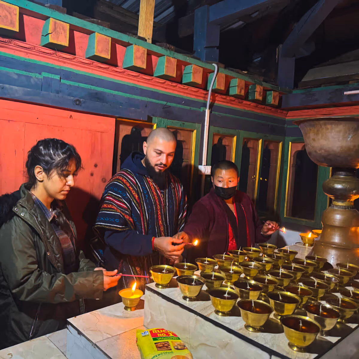 Visitors lighting butter lamps with a monk at Dodeydra Monastery in Bhutan.