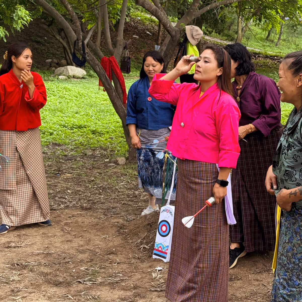 Woman aiming khuru dart during outdoor game in Bhutan.