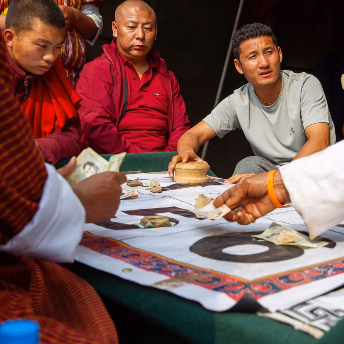 Local men playing a traditional gambling game with stones and money.