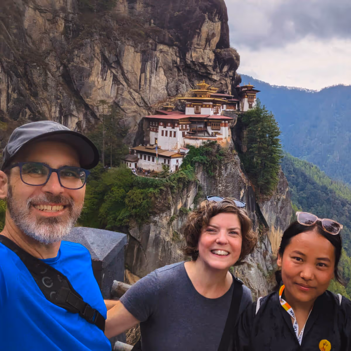 Travelers smiling with guide at Tiger’s Nest backdrop.