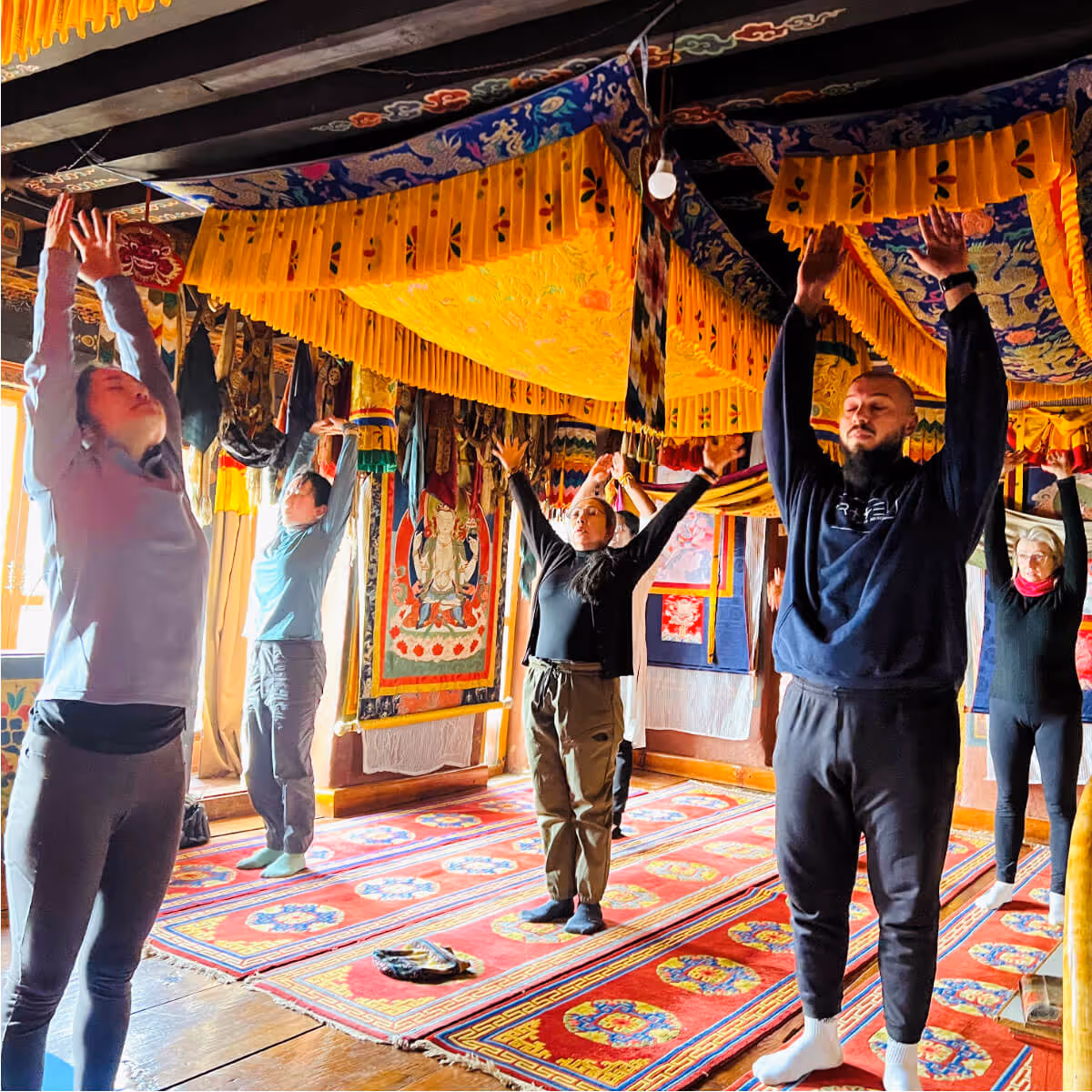 Guests practicing yoga in a monastery adorned with traditional Bhutanese decorations.