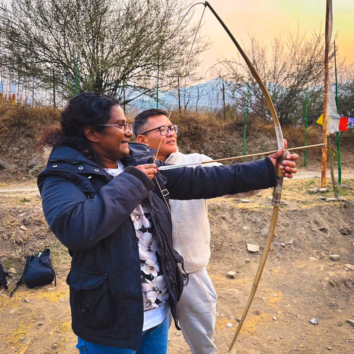 Traveler learning traditional archery in Bhutan with local instructor’s guidance.