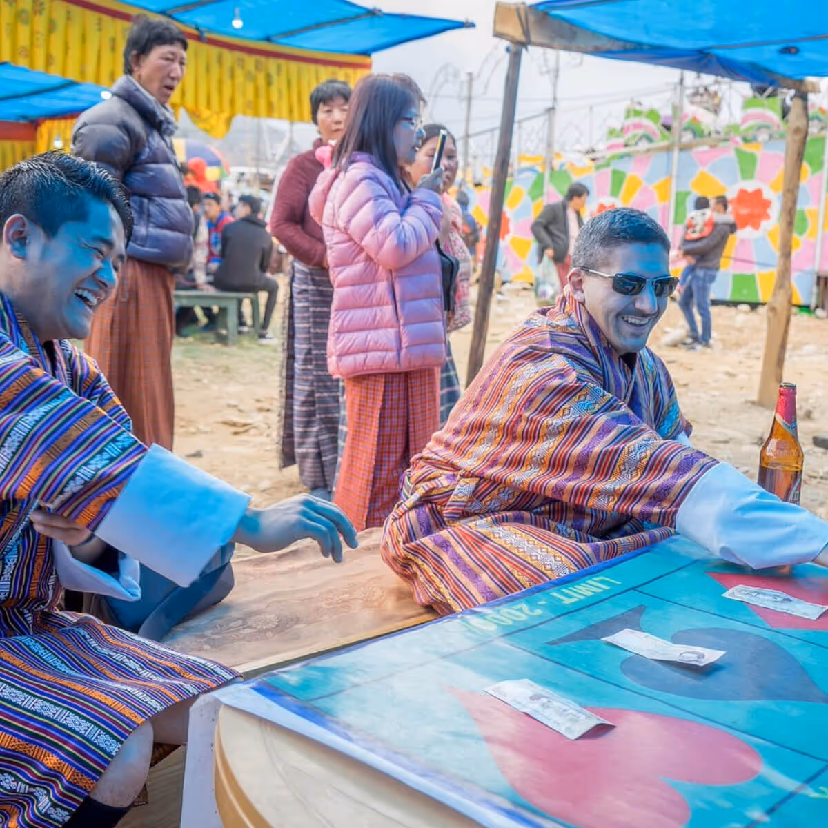 Guests laughing and playing a traditional game at a lively local festival in Bhutan.