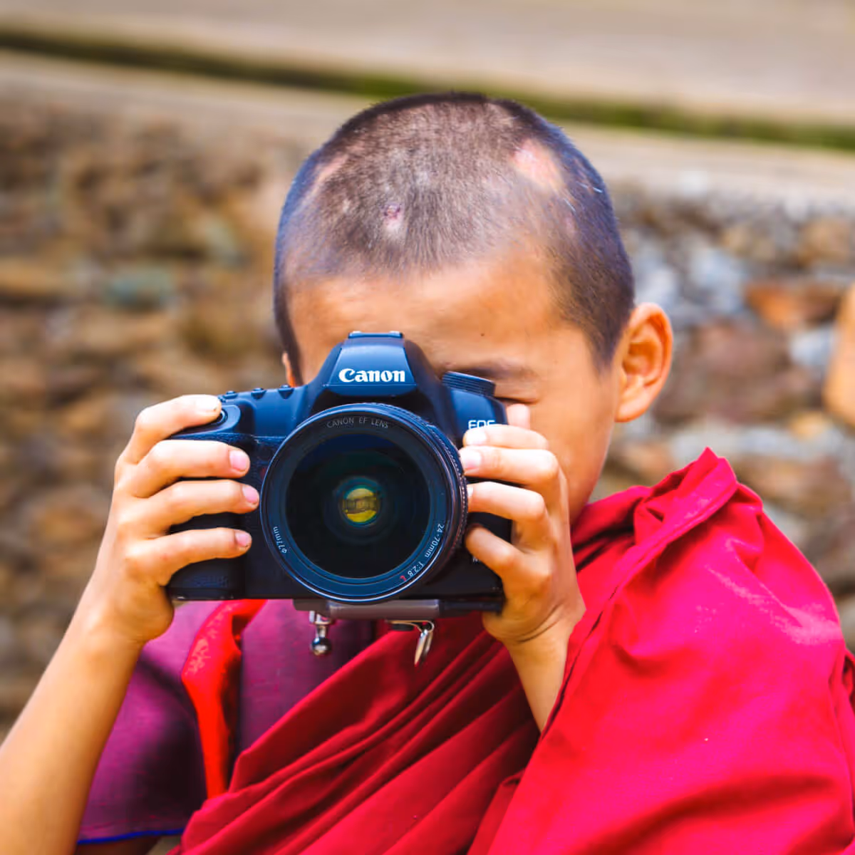 Young monk holding a Canon camera in Bhutan