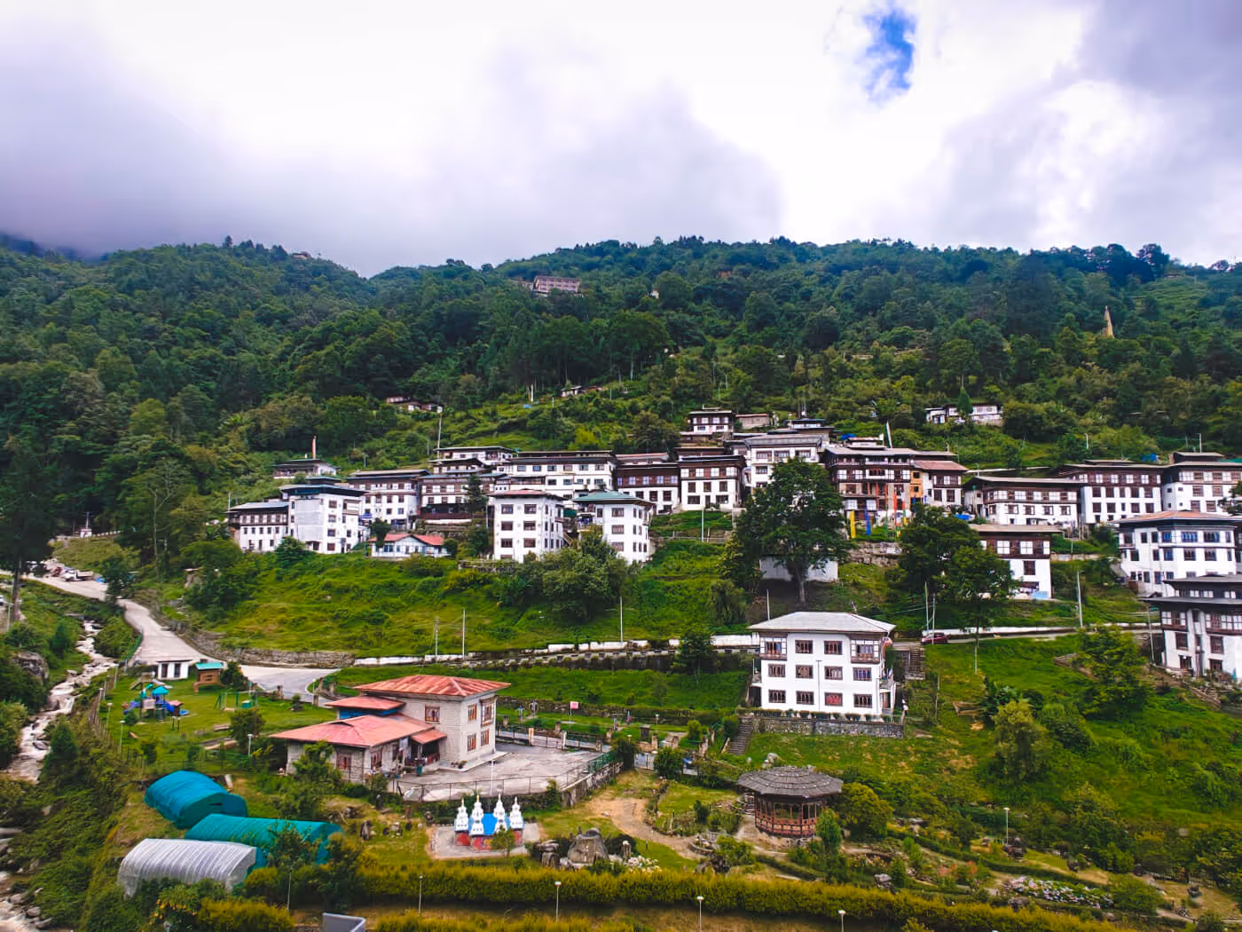 Trongsa town in Bhutan nestled on lush green hillsides, showcasing traditional white buildings and forested mountain backdrop.