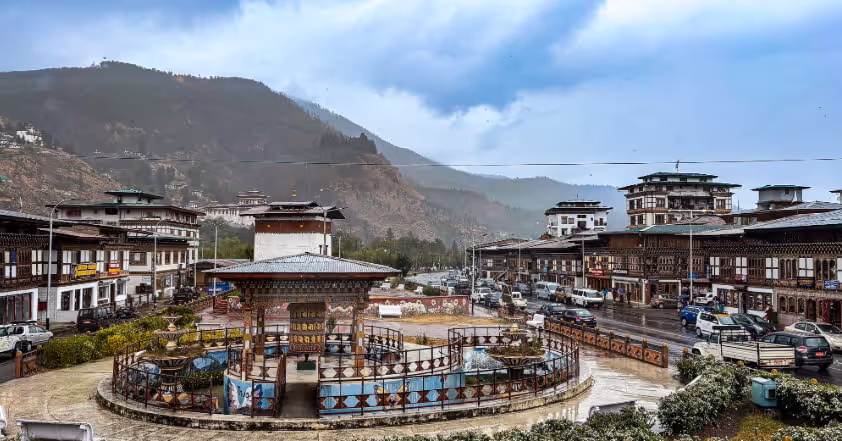Paro town in Bhutan overlooking Rinpung Dzong, Zuri, a stupa, and part of the National Museum, with mountains behind.