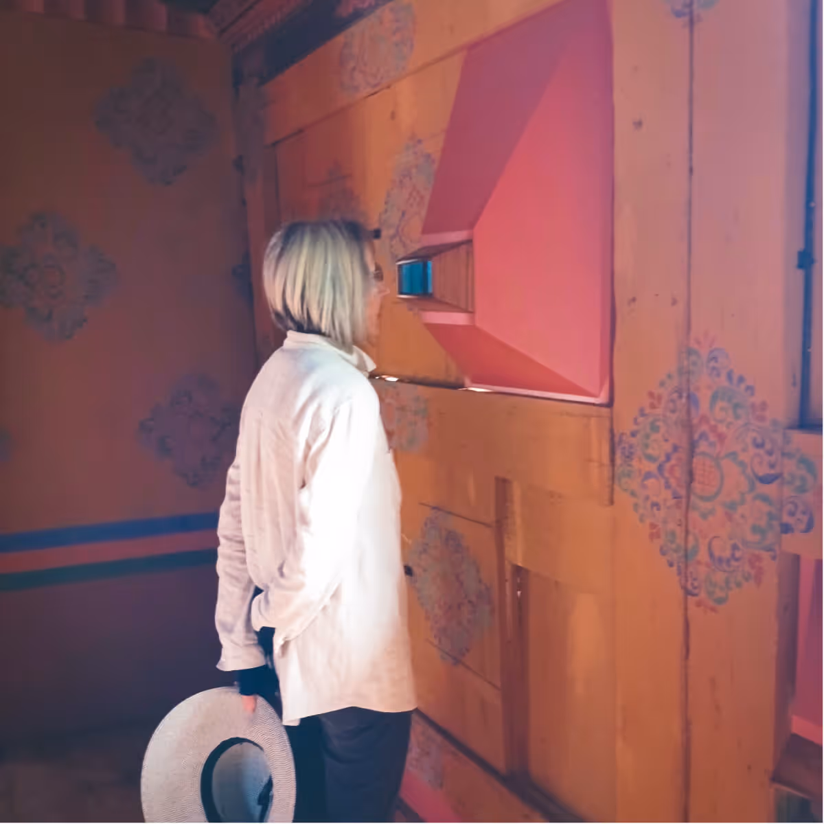 A guest inside Wangdicholing Palace in Bumthang, Bhutan, looking into a traditional-style viewing device displaying historical visuals and text.