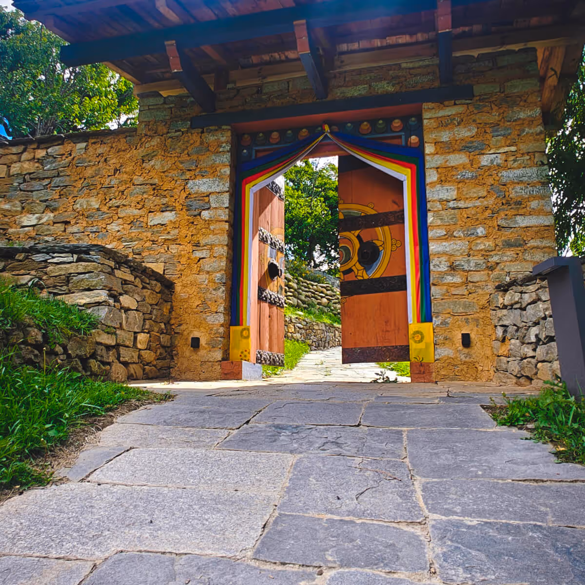 Traditional stone entrance gate with vibrantly painted wooden doors at Wangdicholing Palace in Bumthang, Bhutan.