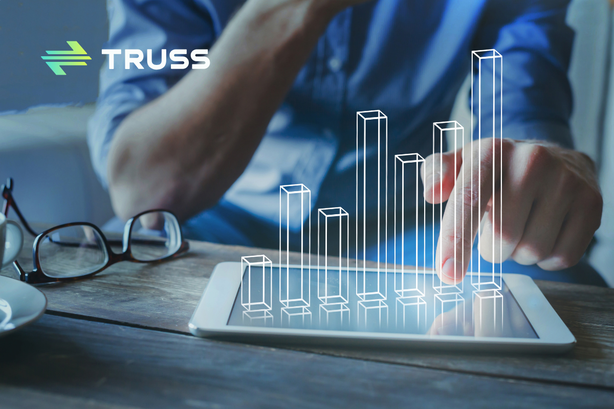 Close-up of a contractor using a tablet with holographic financial graphs, symbolizing digital construction accounting and capital cost management powered by Truss.