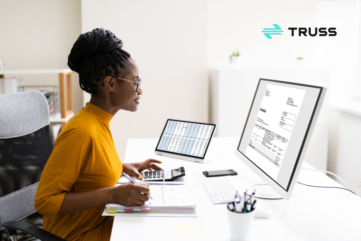 Construction bookkeeper using accounting software and digital spreadsheets to manage invoices and expenses, representing accounting services for construction companies.