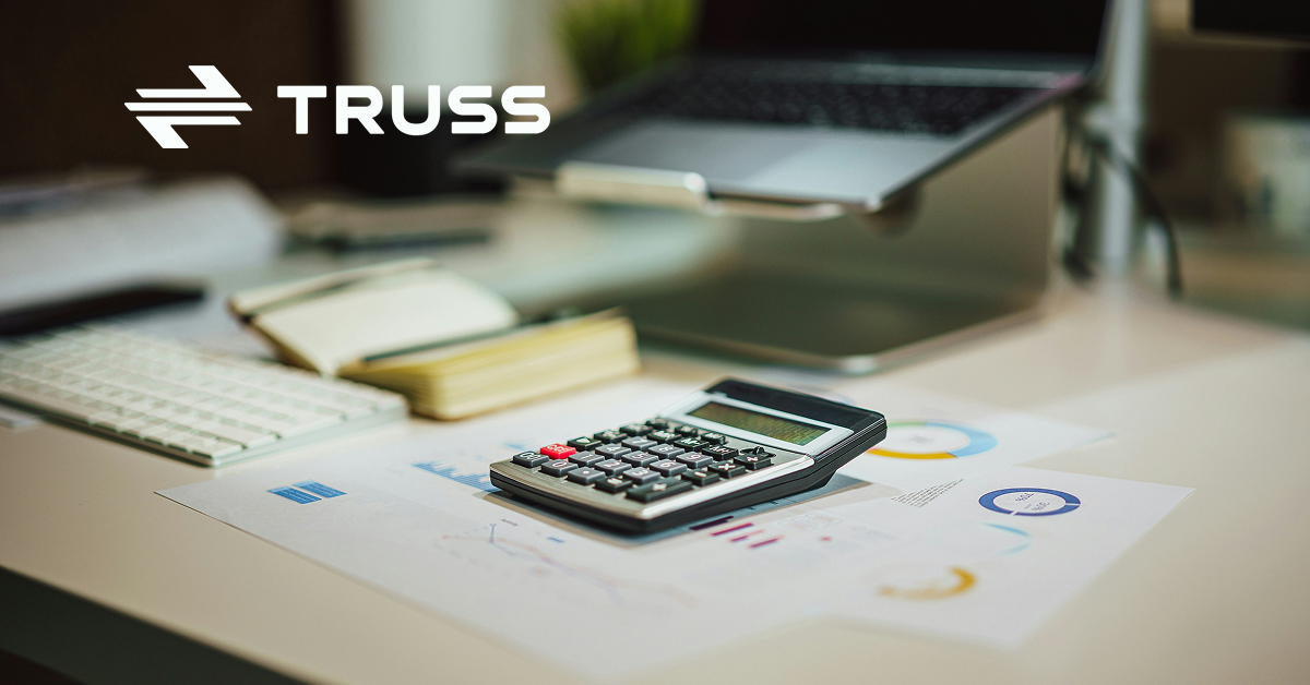 Calculator on financial charts with a laptop and keyboard on a desk, symbolizing how 51Թ helps contractors track construction job costs accurately.