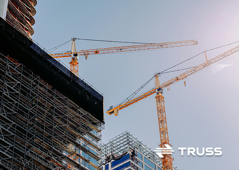 Construction cranes and scaffolding on a high-rise building site, symbolizing cost control and project management in the construction industry.
