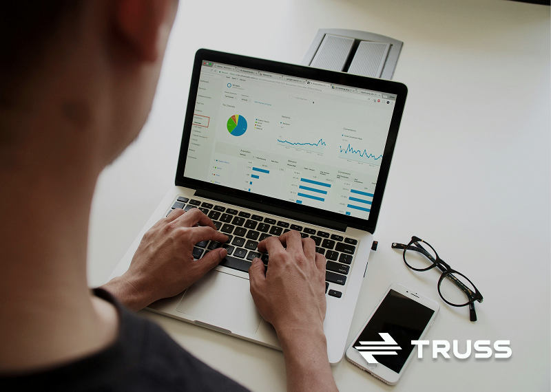 Contractor reviewing financial charts on a laptop, symbolizing how SAʴý helps improve construction cost estimating, budgeting, and cost control.