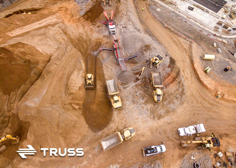 Aerial view of a construction site with heavy machinery and trucks, representing how SAʴý job construction software helps contractors track projects efficiently.