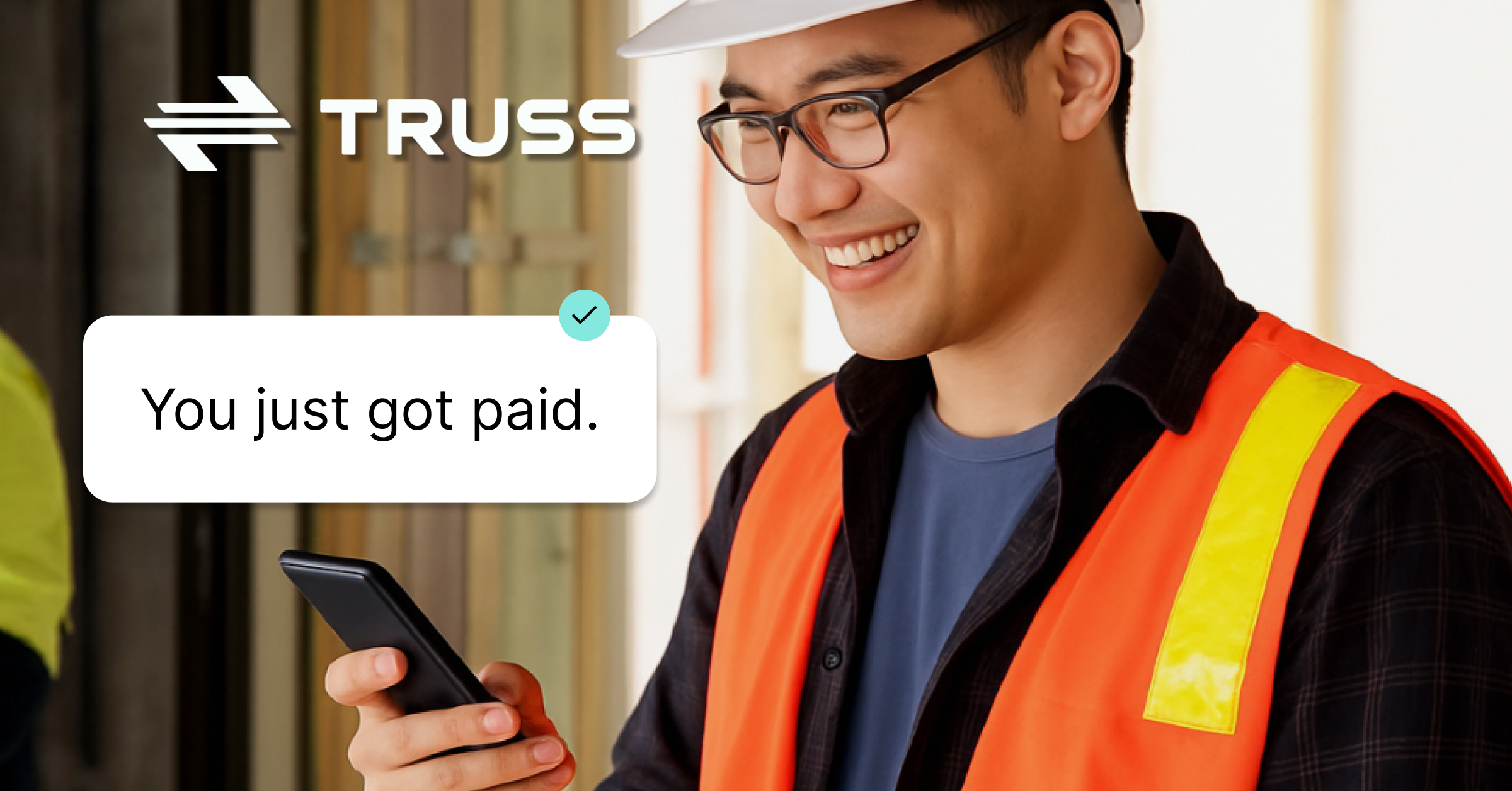 Construction worker smiling while receiving a “You just got paid” notification on his phone, wearing safety gear and standing on a jobsite with the Truss logo above.