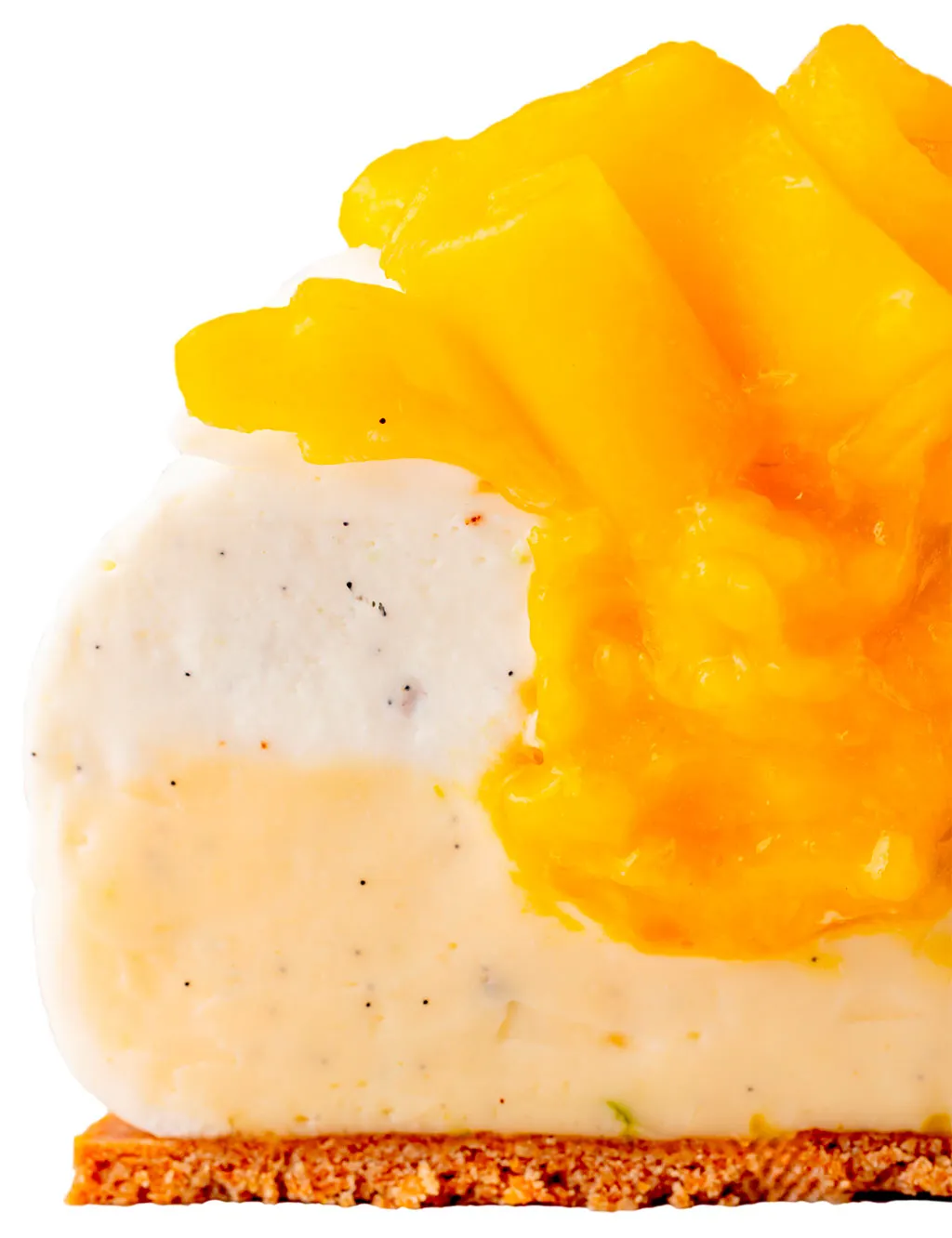 A creation from Maison de Haute Patisserie, features layers of cream with vanilla specks and a crumbly base, adorned with glossy, vibrant yellow mango pieces.