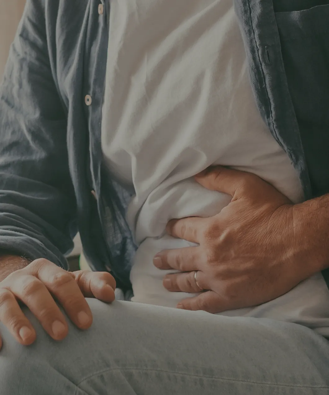 Person holding their stomach with one hand, showing discomfort or pain.