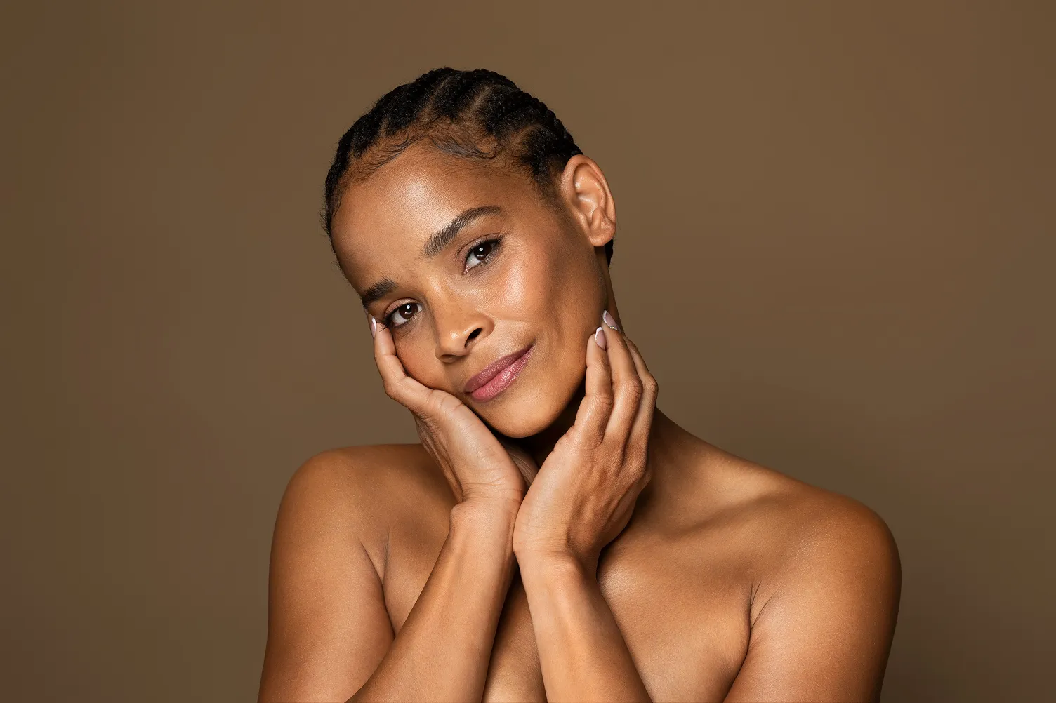 A woman smiling while touching her face