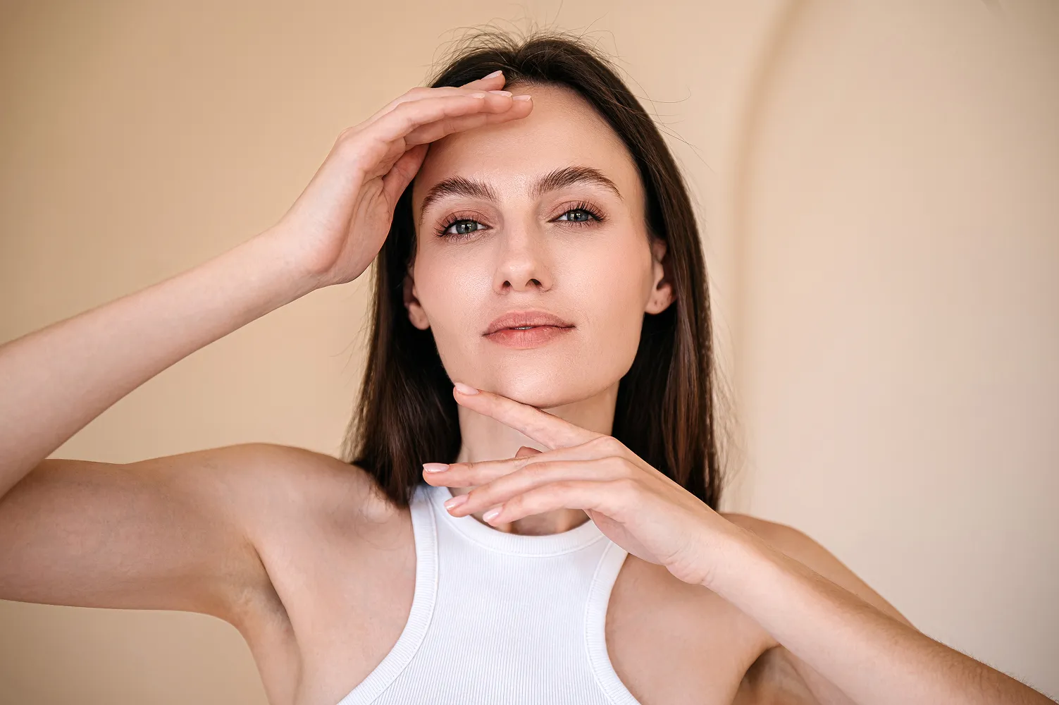 A woman smiling while touching her face