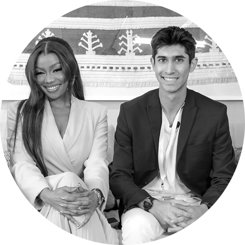 Smiling man and woman sitting side by side in smart casual business attire on a patterned couch.