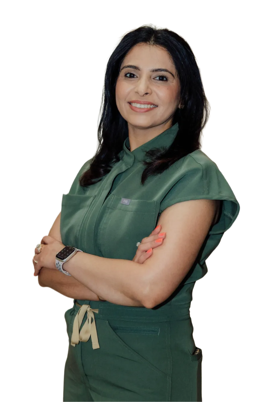 Smiling woman with dark hair wearing a green outfit with arms crossed, accessorized with a smartwatch and rings. she is best dentist in humble, tx