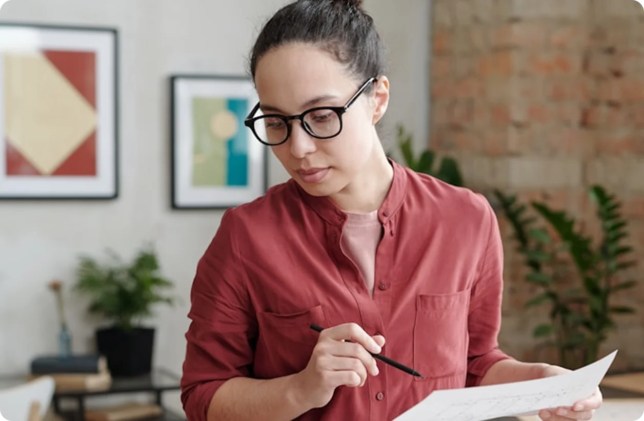 Mujer con gafas usando un teléfono móvil frente a una laptop, con una pantalla de factura digital de Verifactu superpuesta.