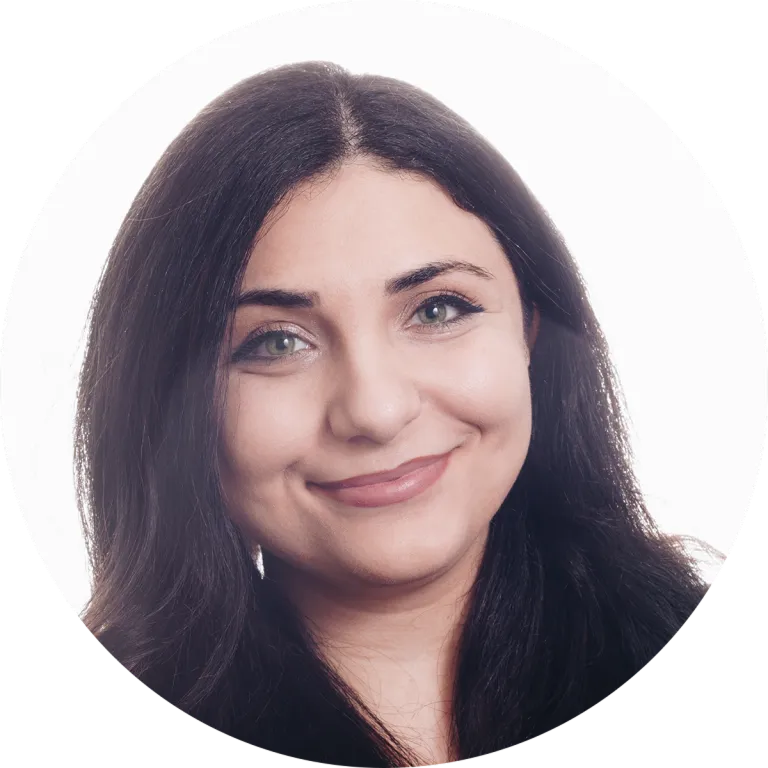 Close-up portrait of a smiling woman with long dark hair and light makeup against a white background.