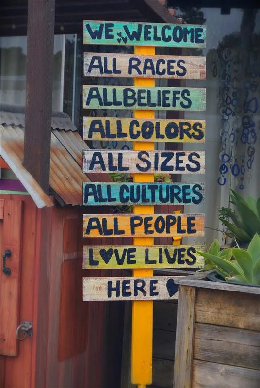 Colorful wooden sign with messages welcoming all races, beliefs, colors, sizes, cultures, people, and love lives here.
