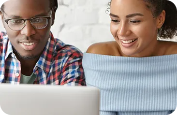 Two people smiling and looking at a laptop screen together.