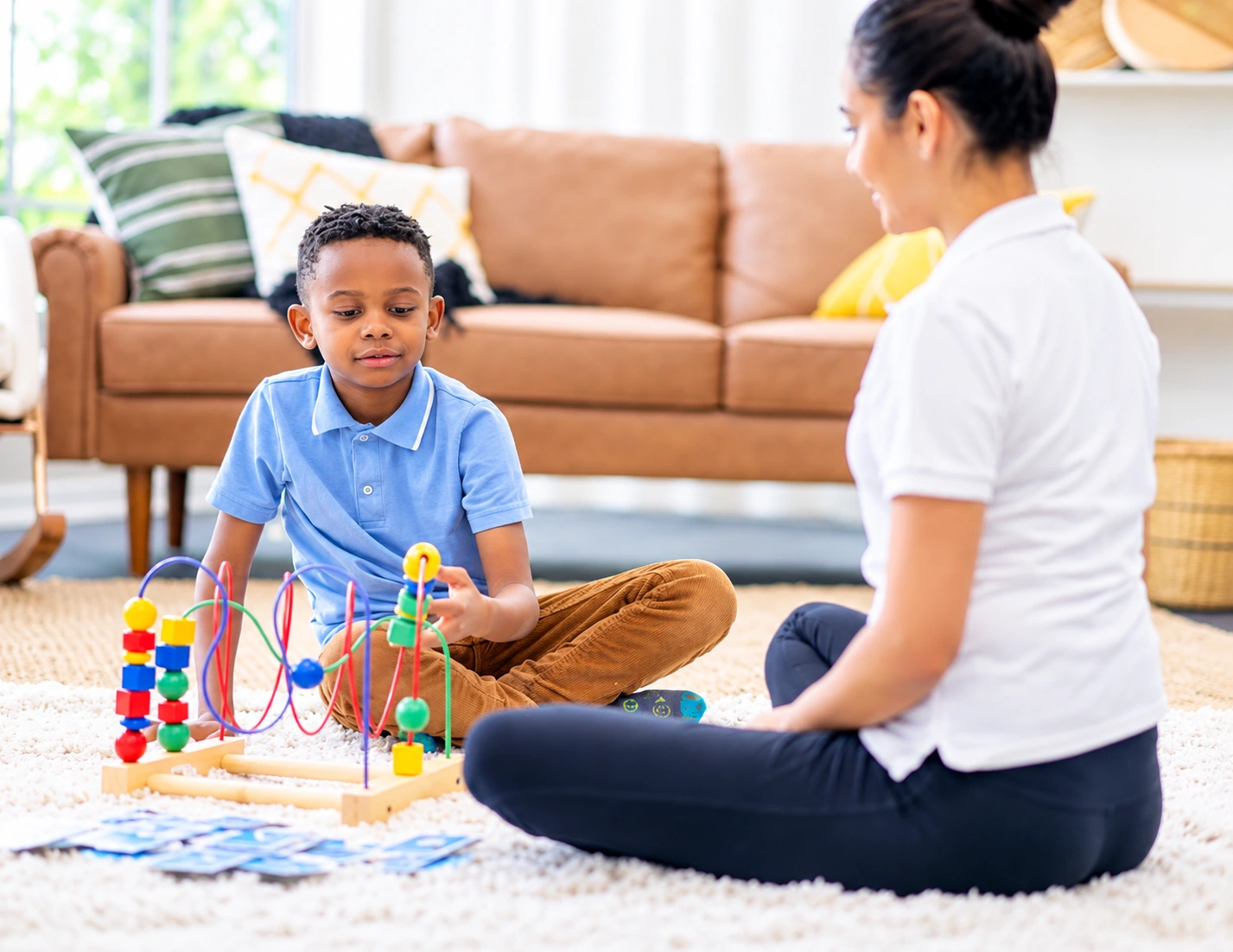A child playing with blocks and toys alongside a therapist.