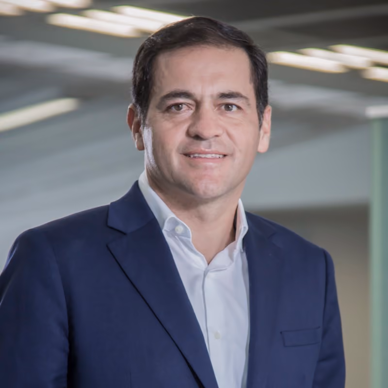 Ejecutivo sonriendo frente a un entorno moderno y profesional en una oficina.