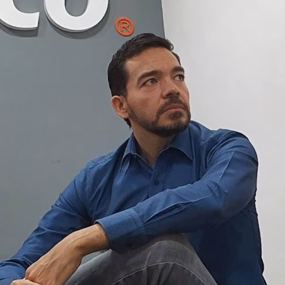 Ejecutivo pensativo sentado frente a un fondo con el logotipo de Cobre.