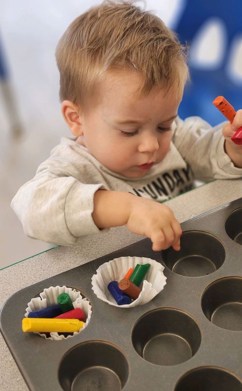 A cute toddler with a baking tray and crayons