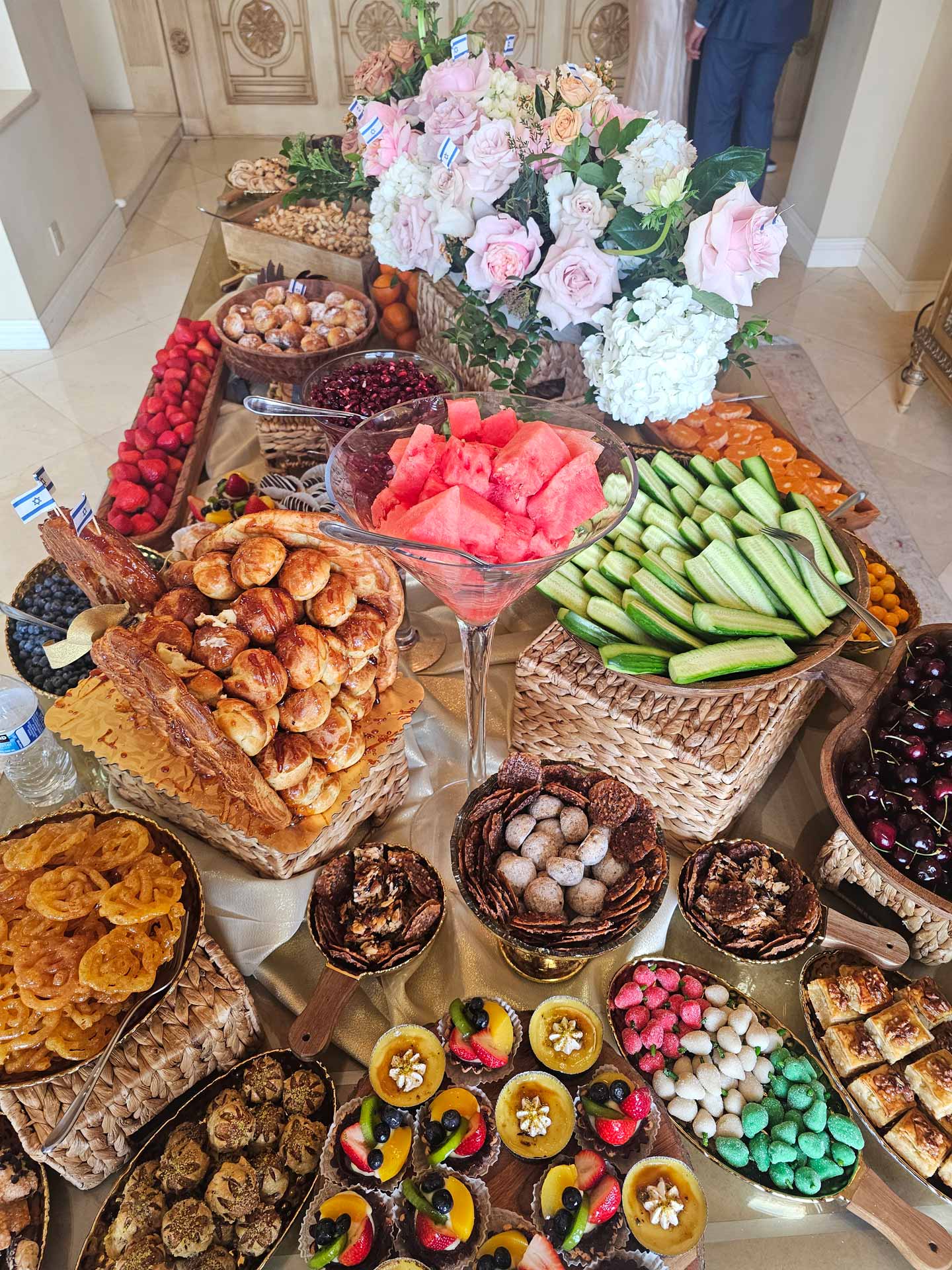 A diverse array of food items displayed on a table, featuring fruits, salads, meats, and desserts in vibrant colors.