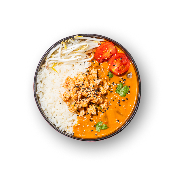 Eine Schüssel leuchtend orangefarbenes Curry mit Tofu, garniert mit Sesamsamen und Koriander. Dazu gibt es weißen Reis, Sojasprossen und Tomatenscheiben.