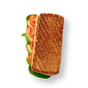 Gegrilltes Panini auf schwarzem Hintergrund mit sichtbaren Schichten aus frischem Salat, Tomatenscheiben und Avocado. Das Sandwich weist Grillstreifen auf, die auf Wärme hindeuten.