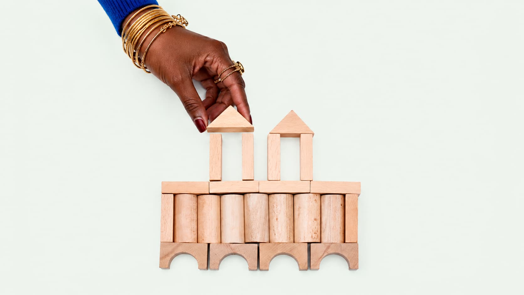 A hand places a wooden block atop a bridge-like structure, symbolizing how bridging loans connect the gap in a property purchase.