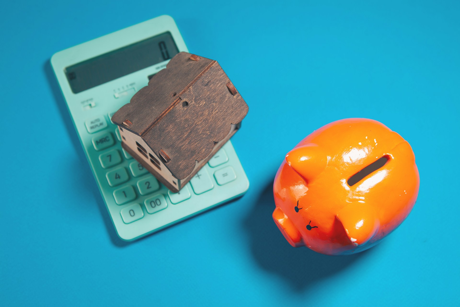 Model house on a calculator with a piggy bank, illustrating UK mortgages