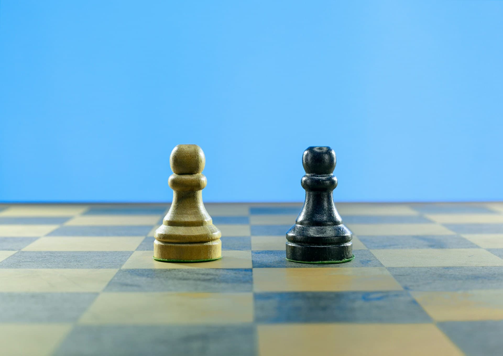 Two chess pawns facing each other on a board, representing bridging loan vs mortgage for UK property finance