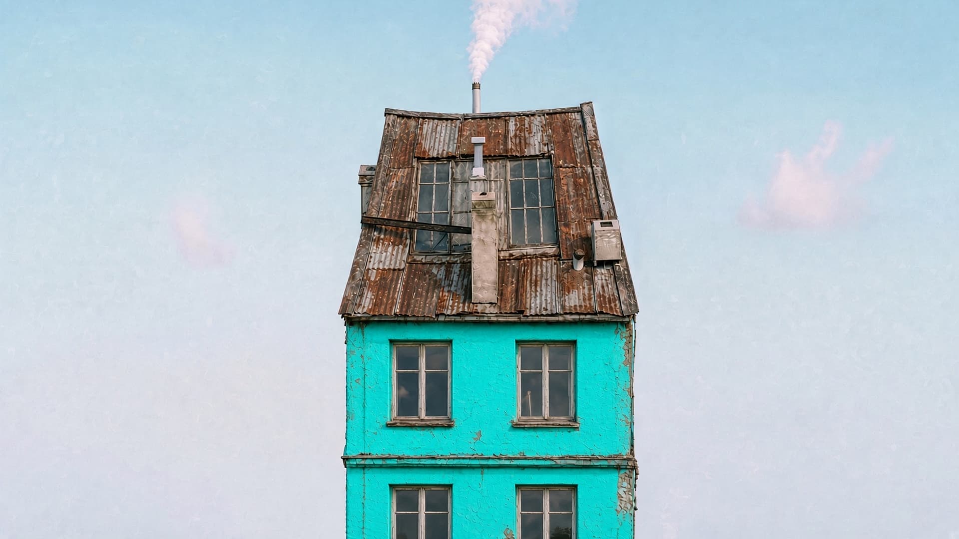 A tall turquoise house with a rusted corrugated metal roof and peeling render, an example of an unmortgageable property